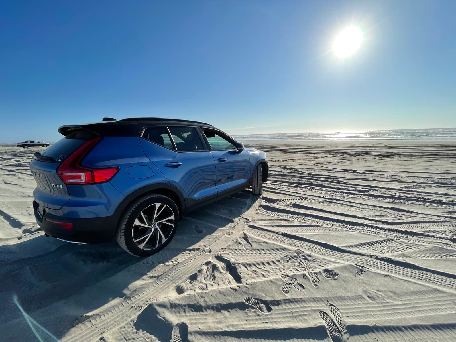 A blue Volvo XC40 parked on the sand at Ocean Park beach under full sun
